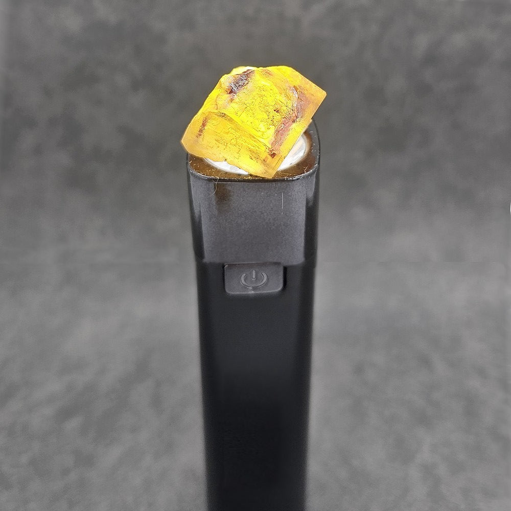Cube de fluorite jaune foncé et violet translucide sous lumière